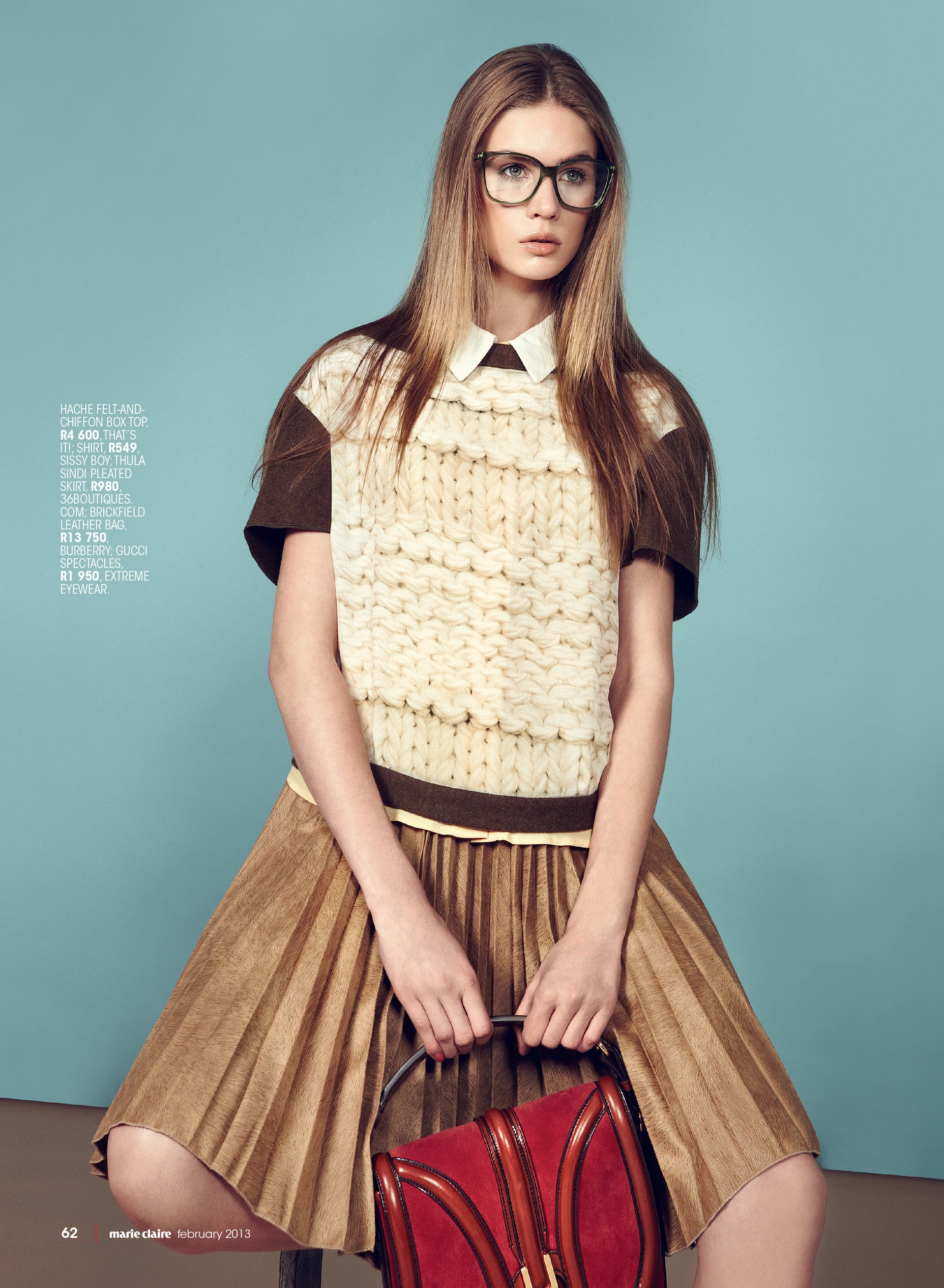 Young woman in a chic white knitted top and brown skirt, wearing glasses, holding a red leather bag against a teal background. Fashion shoot for Marie Claire February 2013.