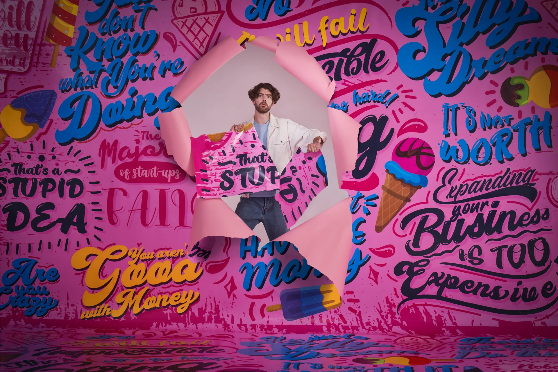 Confident man breaking through a vibrant pink background filled with negative business-related messages, symbolizing overcoming challenges and doubts.