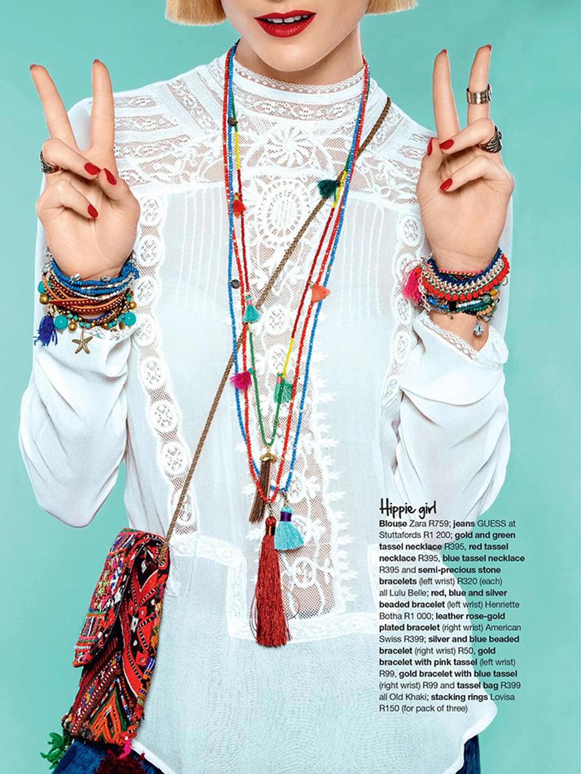 Hippie-inspired woman in a white lace blouse, adorned with multicolored necklaces, bracelets, and a beaded bag. She makes a peace sign with her hand, against a turquoise background.